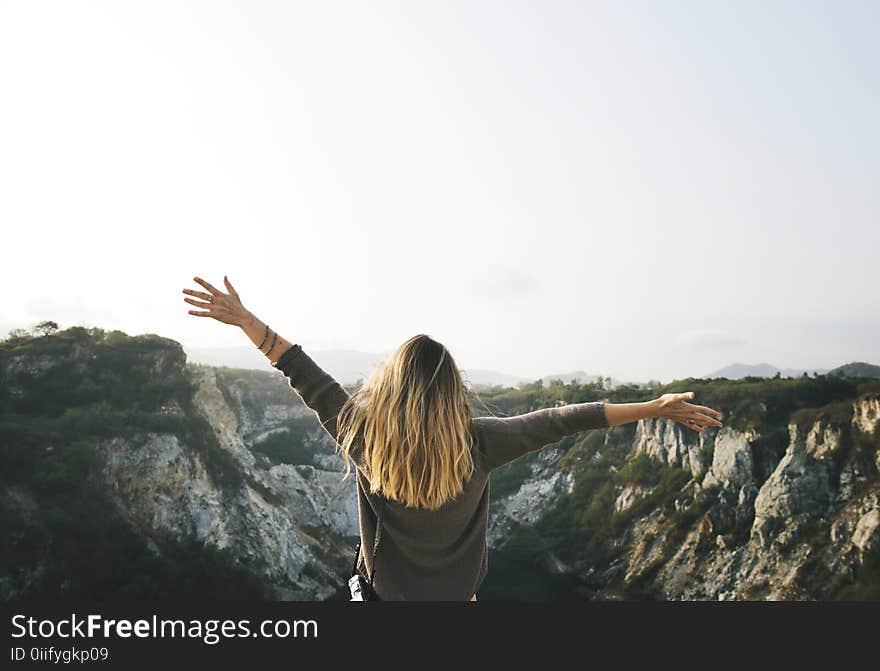 Woman With Blonde Hair at the Top of the Mountain Raising Her Hands