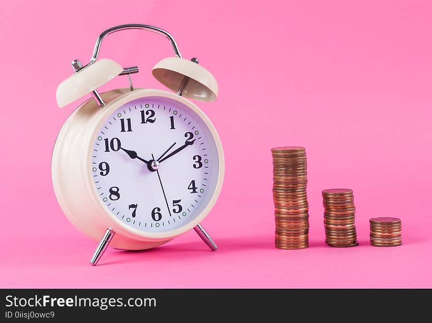 Old clock and golden coins on pink background