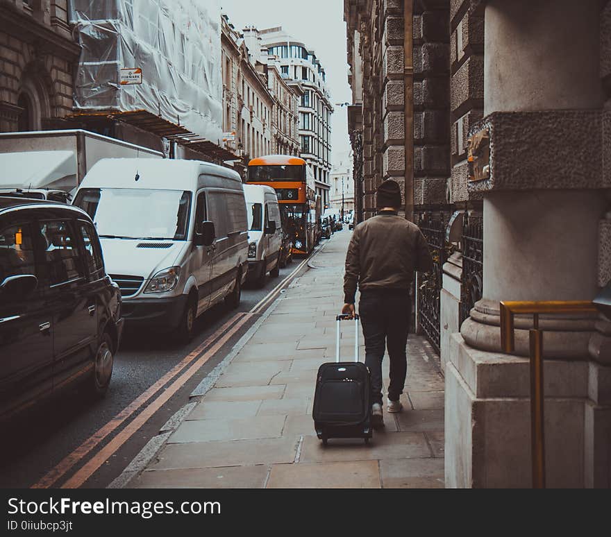 Man in Brown Jacket Holding Black Travel Luggage