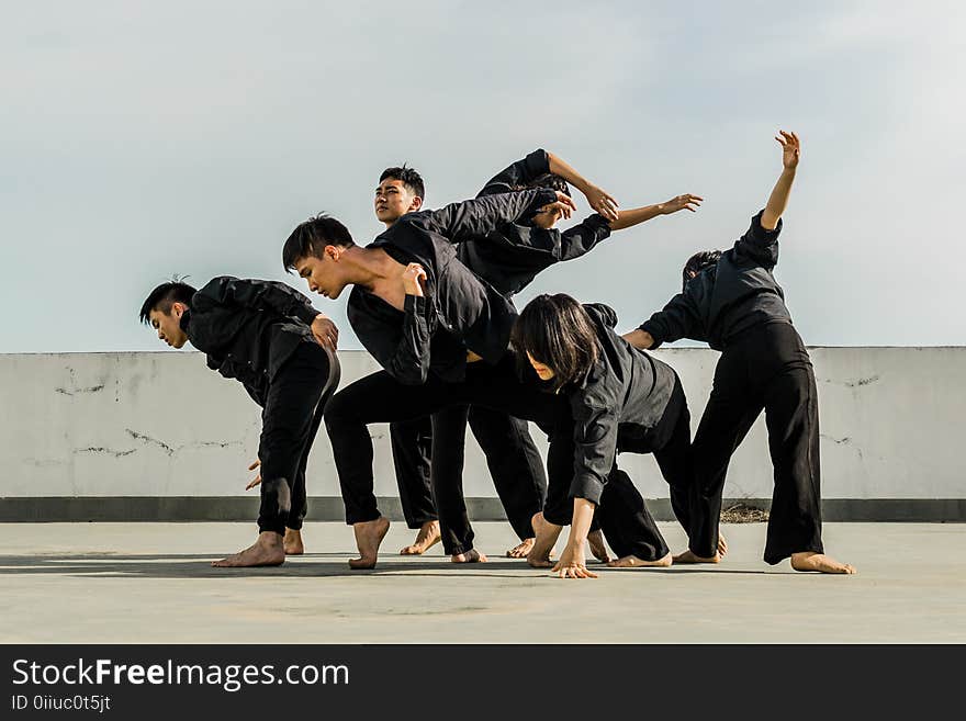 Six People in Black Matching Clothes Dancing at Daytime