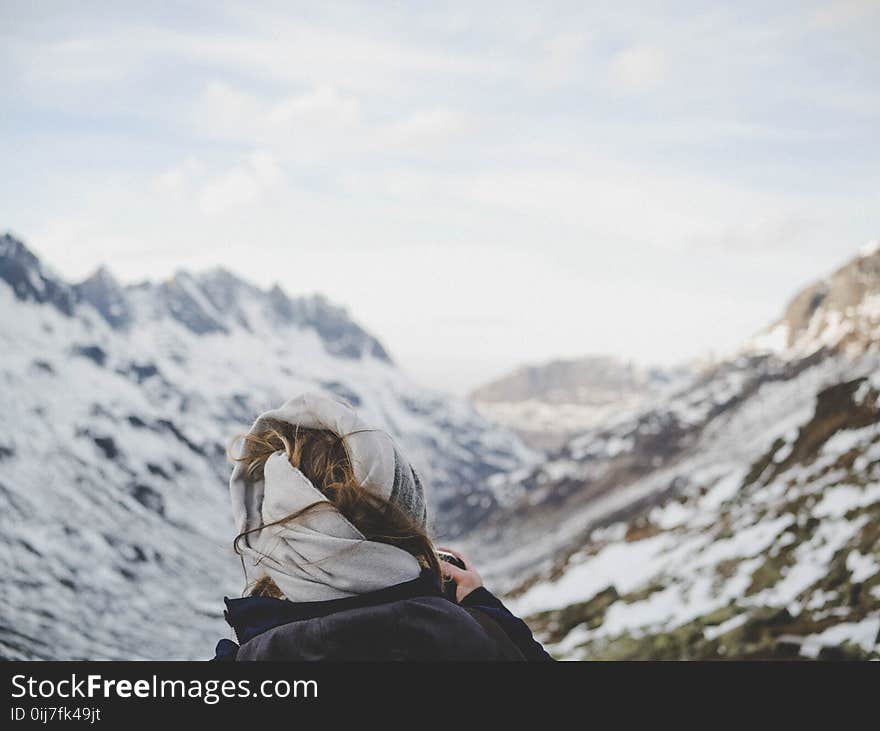 Person Wearing Black Jacket in Front of Mountain Filled With Snow