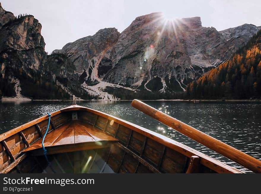 Brown Canoe in the Body of Water Near Mountain