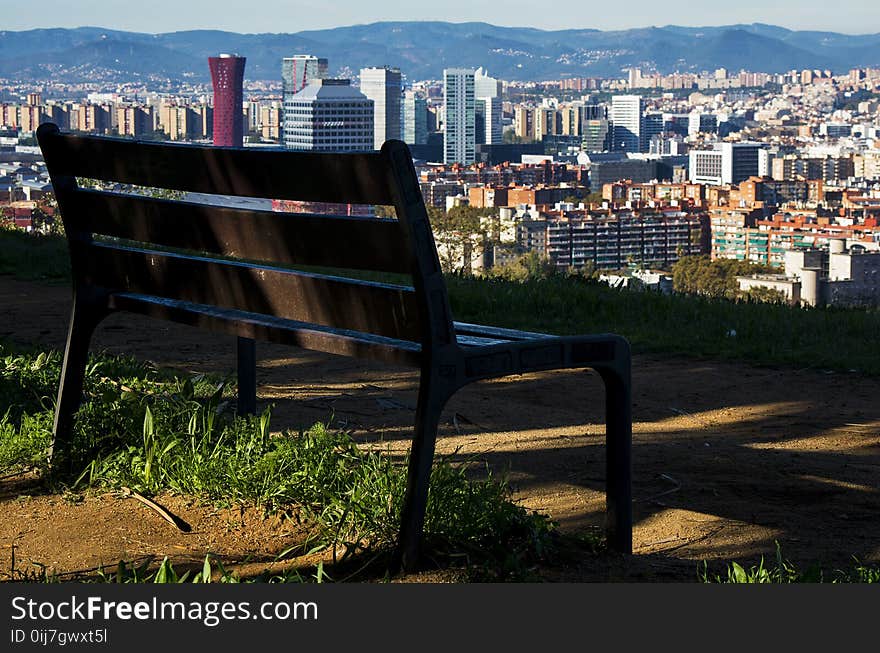 Brown Wooden Bench With Metal Frame Surrounded by Building Scenery