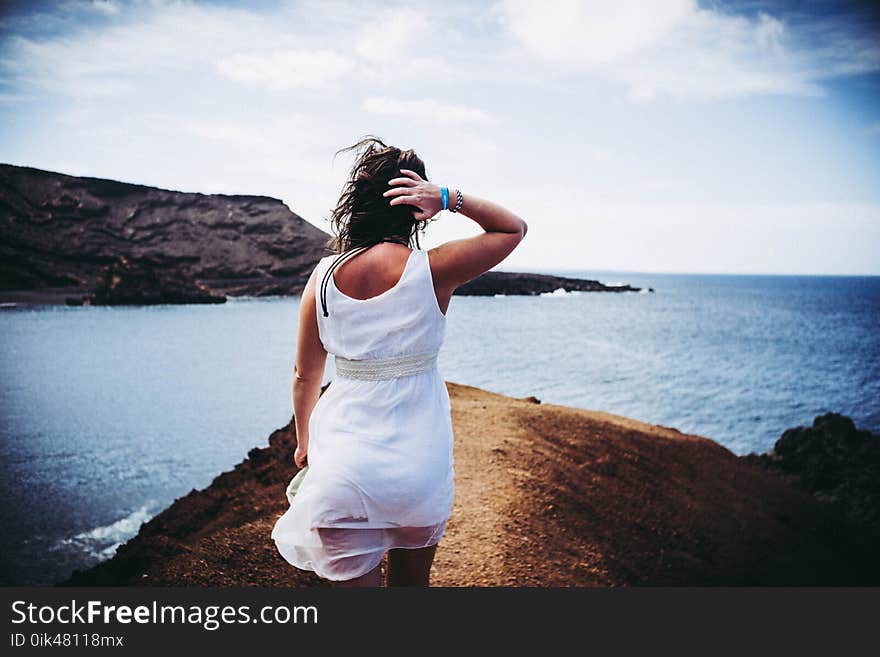 Woman Wearing White Sleeveless Mini Dress on Top of Brown Sand Near Body of Water