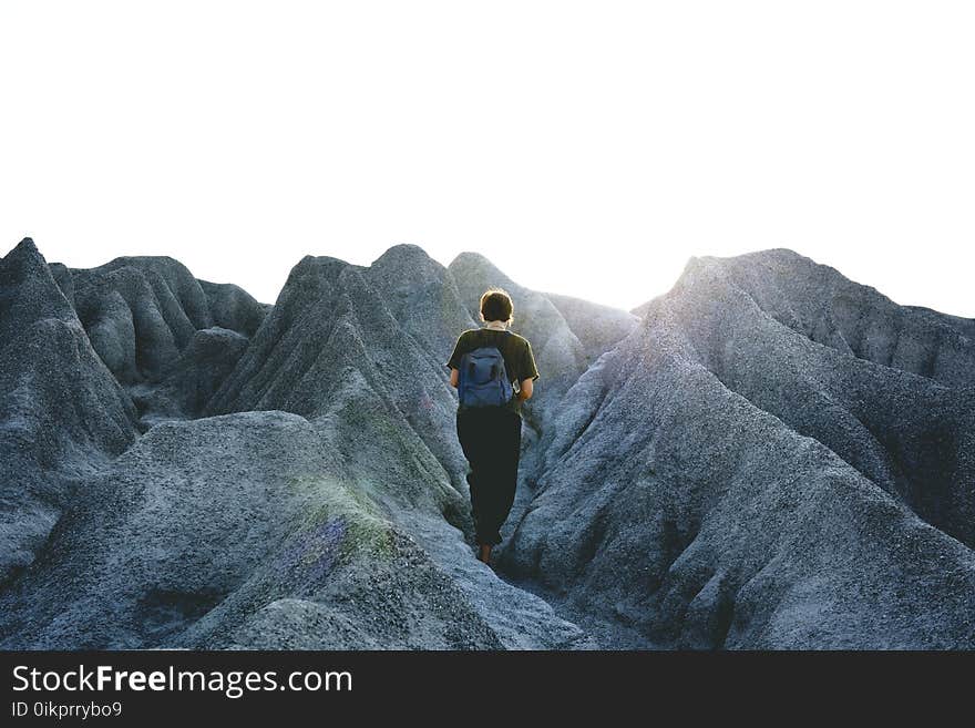 Man in Black Crew Neck Shirt and Pants Walking on Gray Mountain Formations