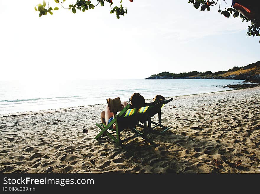 People Lying On Green Wooden Lounger Chairs On Beach