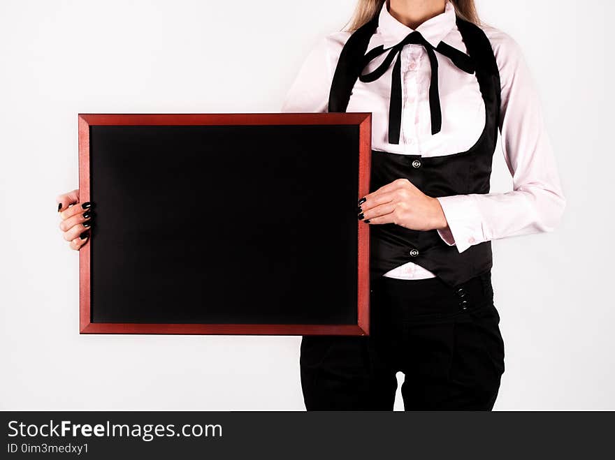 Young elegant girl holding blank drawing blackboard in hands and space for text on board