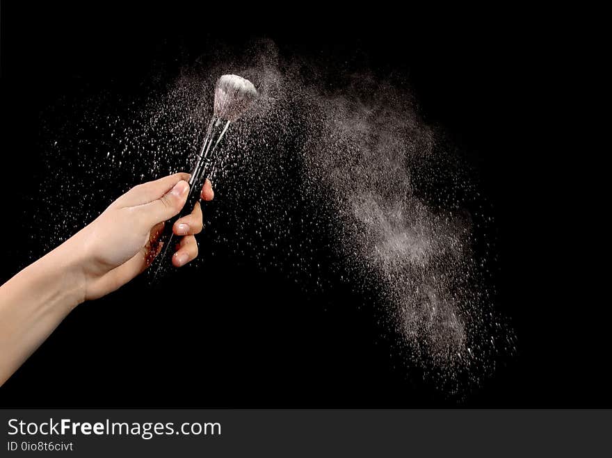 White blusher explosion in young female hand on black background. Close up Make up and Female beauty image concept. White blusher explosion in young female hand on black background. Close up Make up and Female beauty image concept.