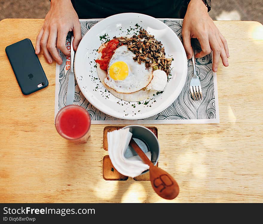 Fried Egg With Plain Rice on White Plate Beside Stainless Steel Fork With Clear Drinking Glass on Top Table