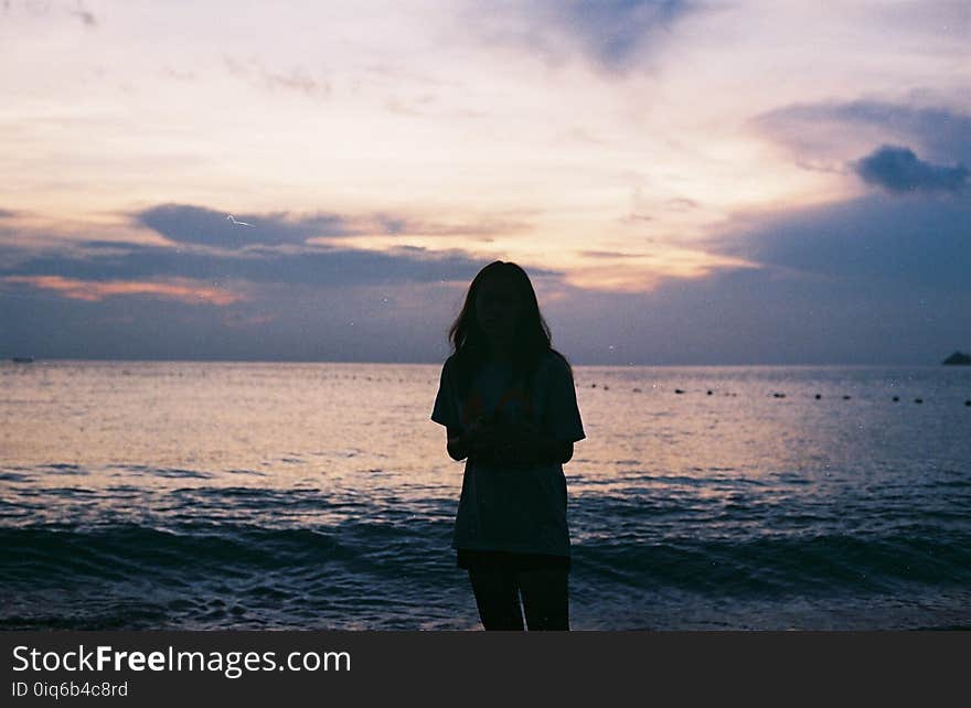 Silhouette of Woman Standing Near Large Body of Water