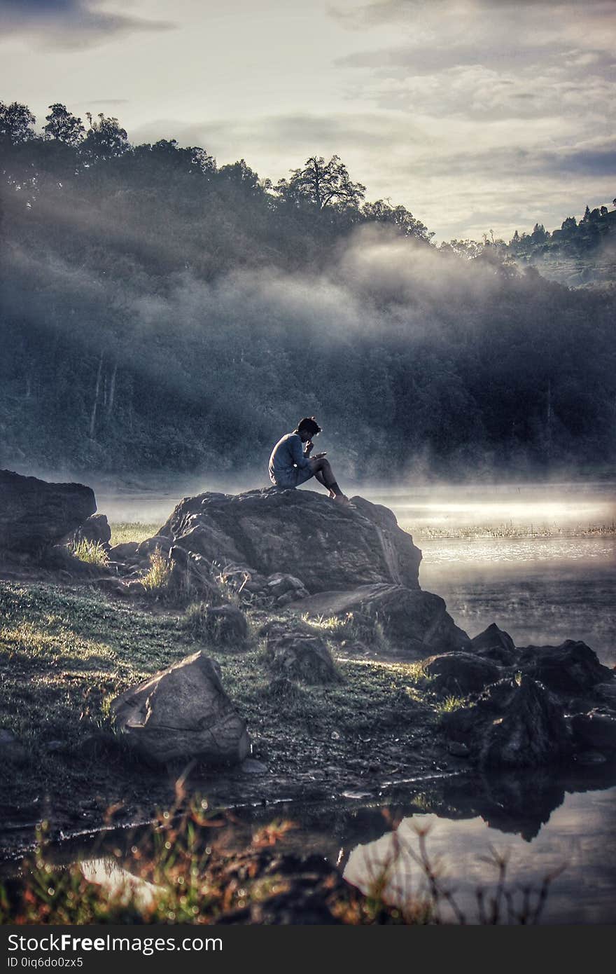 Man in Gray Shit Sitting on Rock Boulder