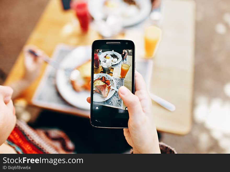 Person Holding Phone Taking Picture of Served Food