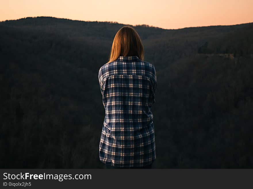 Woman Wearing Blue and White Plaid Dress Shirt in Front of Green Mountain