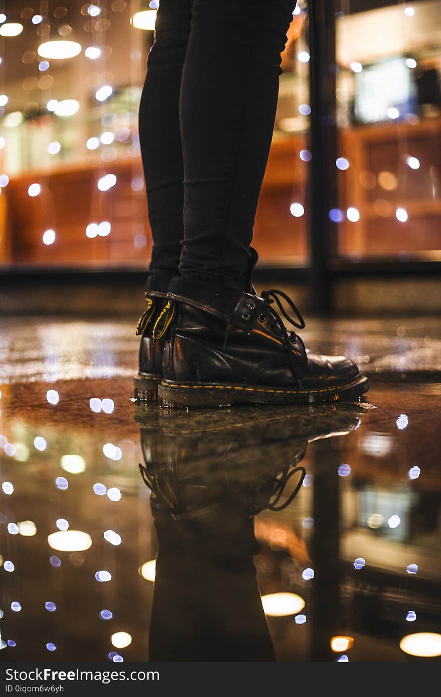 Photo of Person Wearing Black Fitted Jeans and Black Dr.martens Boots Standing on Black Floor Tiles