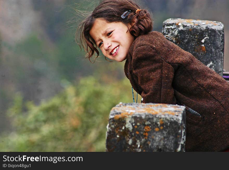 Girl Wearing Brown Coat Leaning On Concrete Pillar