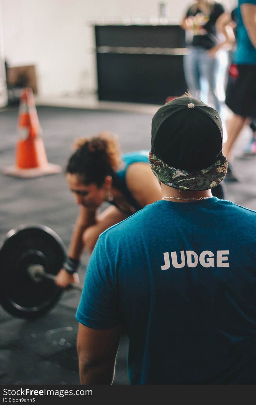 Man in Blue Crew-neck Shirt Staring At Woman Trying To Lift Barbell