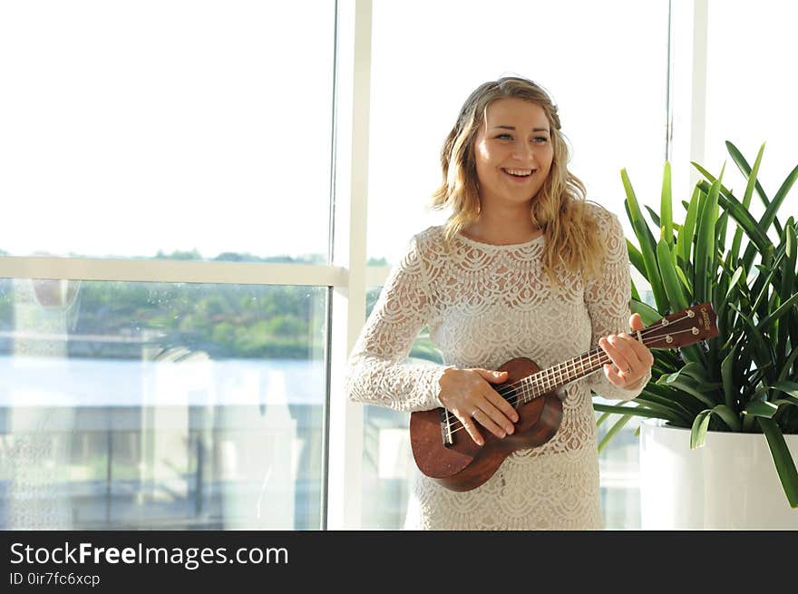 Woman Wearing White Floral Dress Playing Ukulele