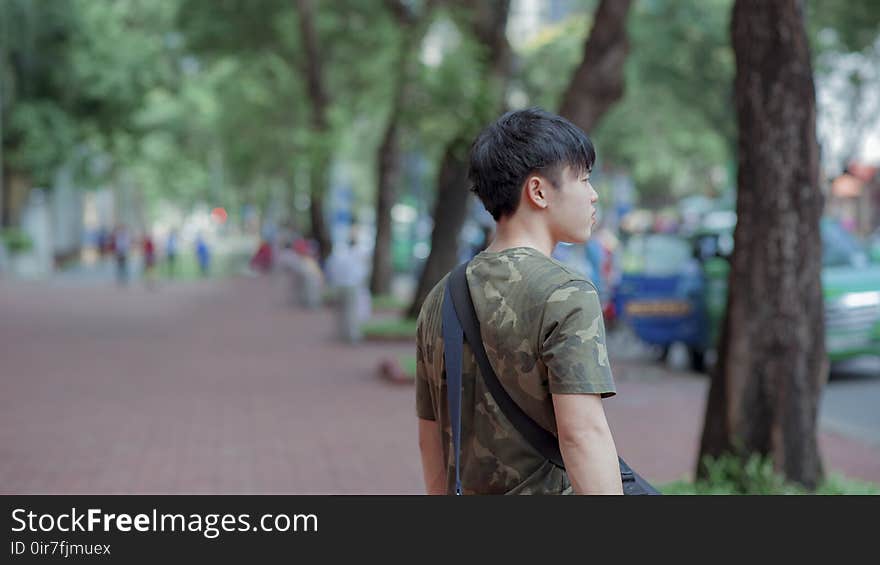 Man in Green and Grey Camouflage Shirt While Standing Behind Tree