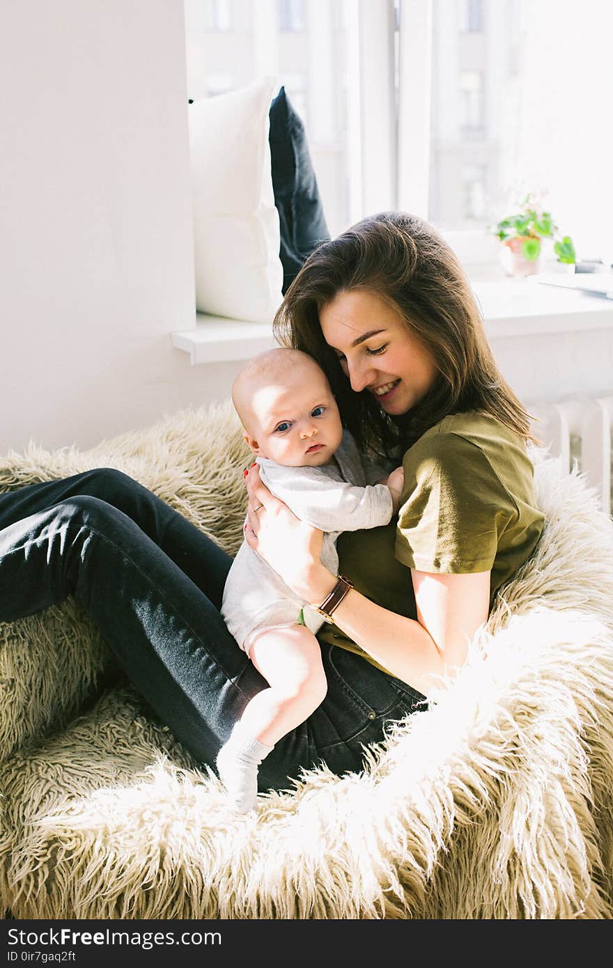 Woman in Green Shirt Holding Baby While Sitting