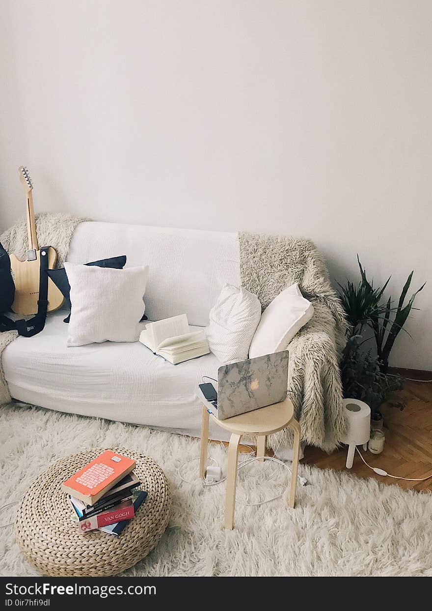 White and Black Laptop Computer on Brown Wooden Stool Near Pile Books