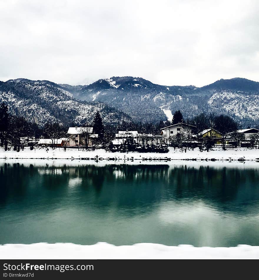 White Houses in Front of Mountains Under White Cloudy Sky