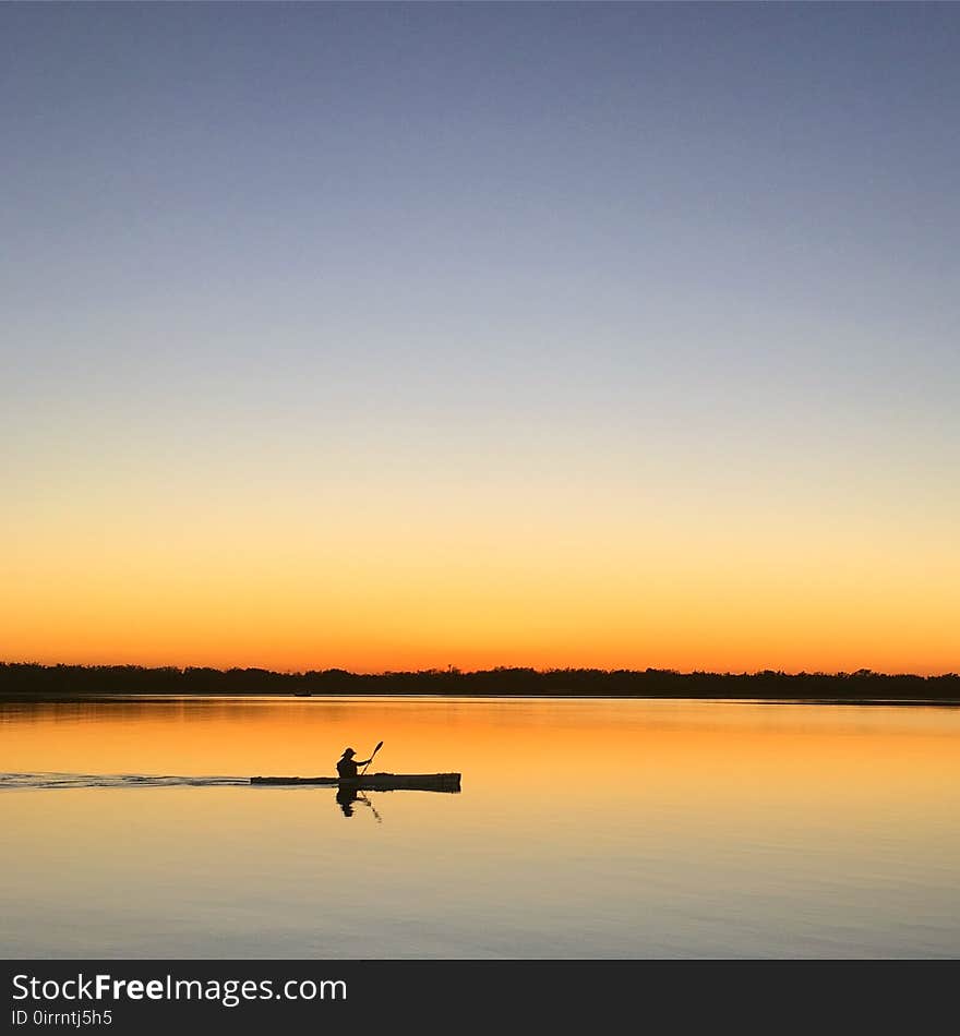 Silhouette of Man Inside of Boat Sailing on Body of Water during Sunset