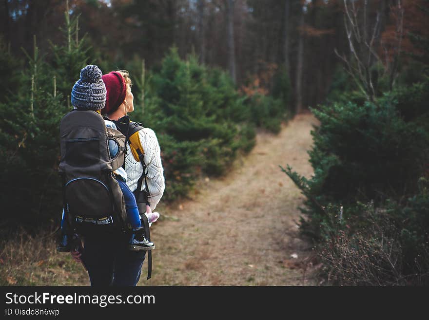 Shallow Focus on Blond Haired Woman in White Long Sleeve Shirt Carrying a Baby on Her Back