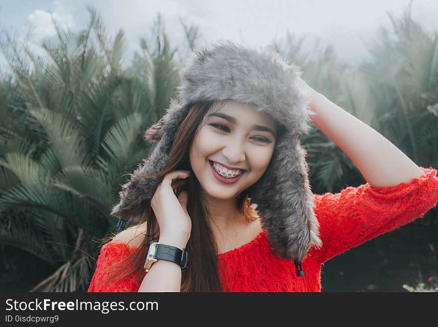 Woman In Red Off Shoulder Top Wearing Fur Beanie Smiling for Photo