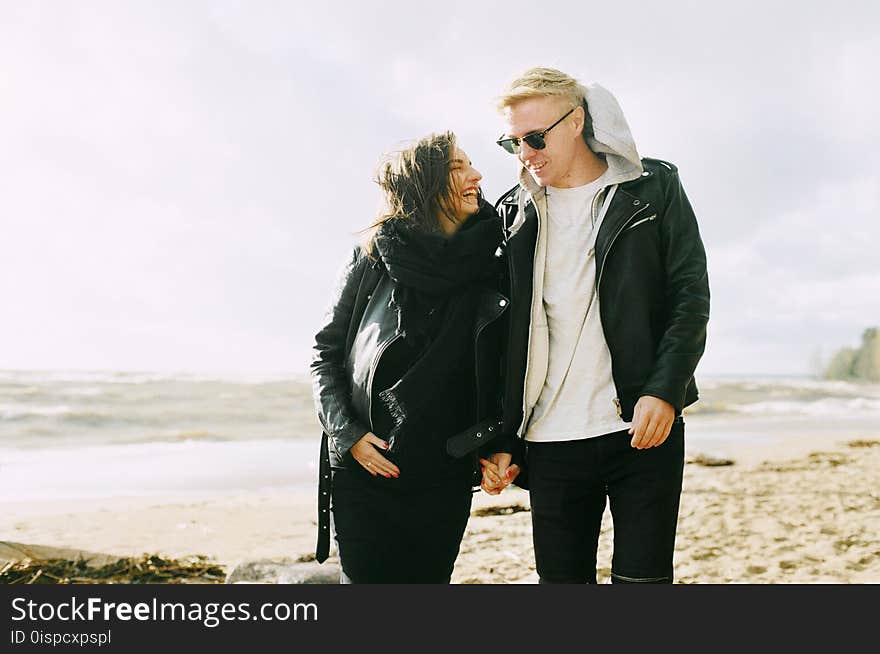 Man and Woman Wearing Jackets Near Seaside Under Cloudy Sky