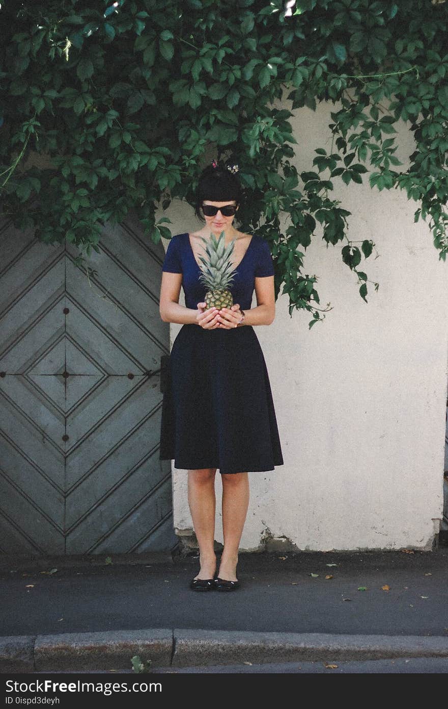 Woman Holding Pineapple Standing Beside Wall