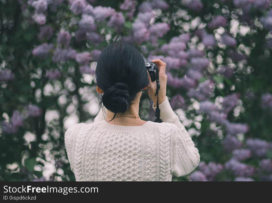 Woman Holding Camera Taking Photos of Flowers