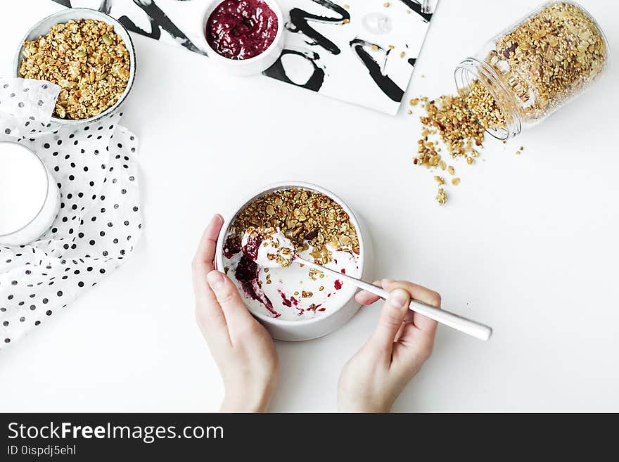 Person Mixing Cereal, Milk, and Strawberry Jam on White Ceramic Bowl