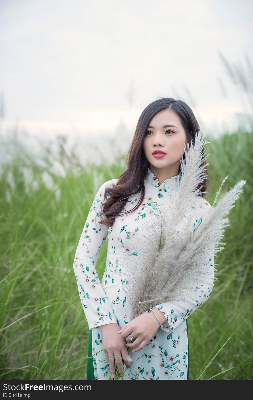 Woman in White and Green Long-sleeved Traditional Dress Standing Next-to Green Grasses