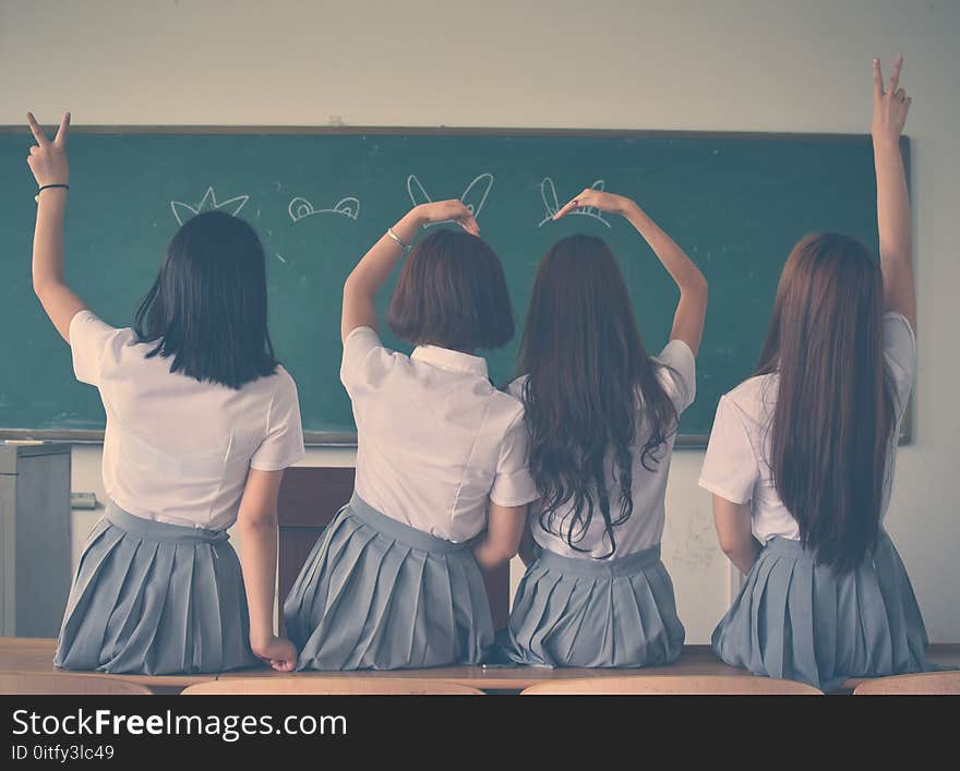 Photo of Four Girls Wearing School Uniform Doing Hand Signs