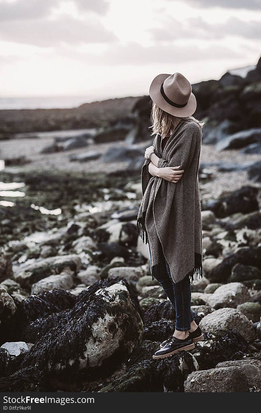 Woman Wearing Draped Coat Standing on Rock Facing Mountain