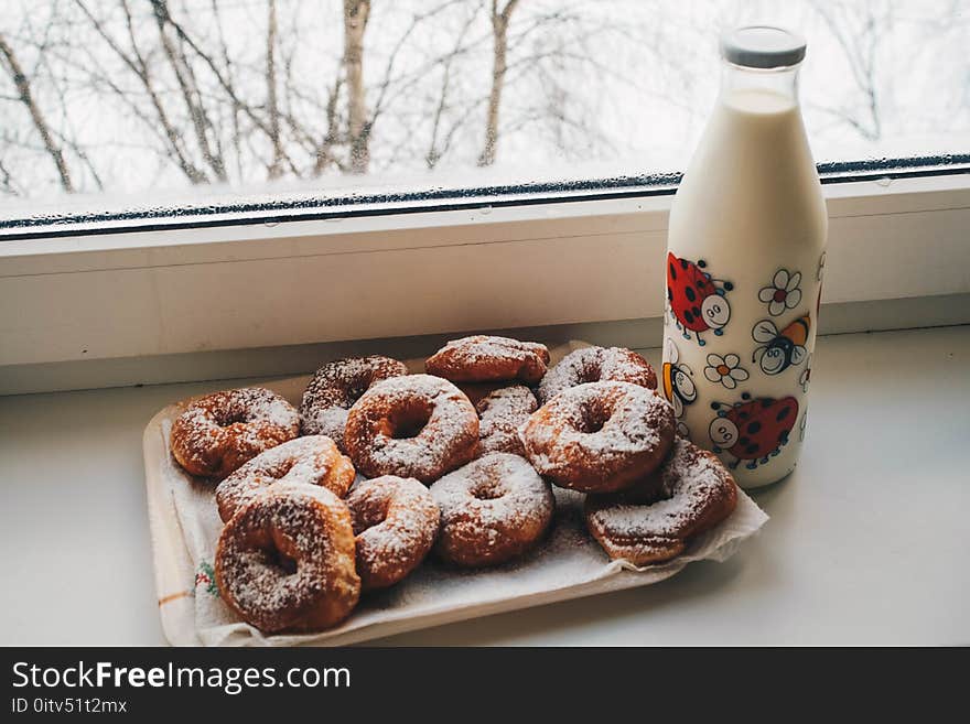 Doughnuts and Milk Bottle Near Clear Glass Window