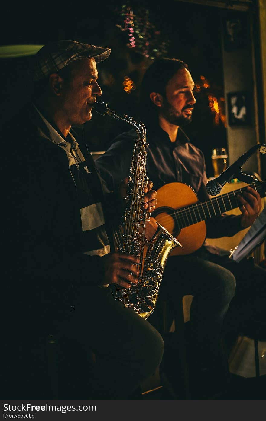 Two Men Playing Saxophone and Acoustic Guitar during Night Time