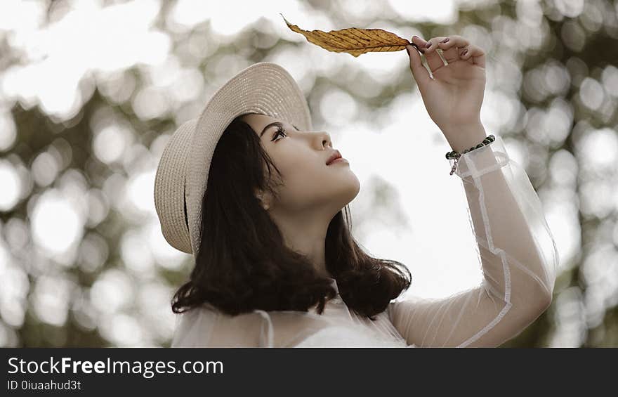 Woman Wearing White Long Sleeve Scoop-neck Top While Holding Brown Leaf