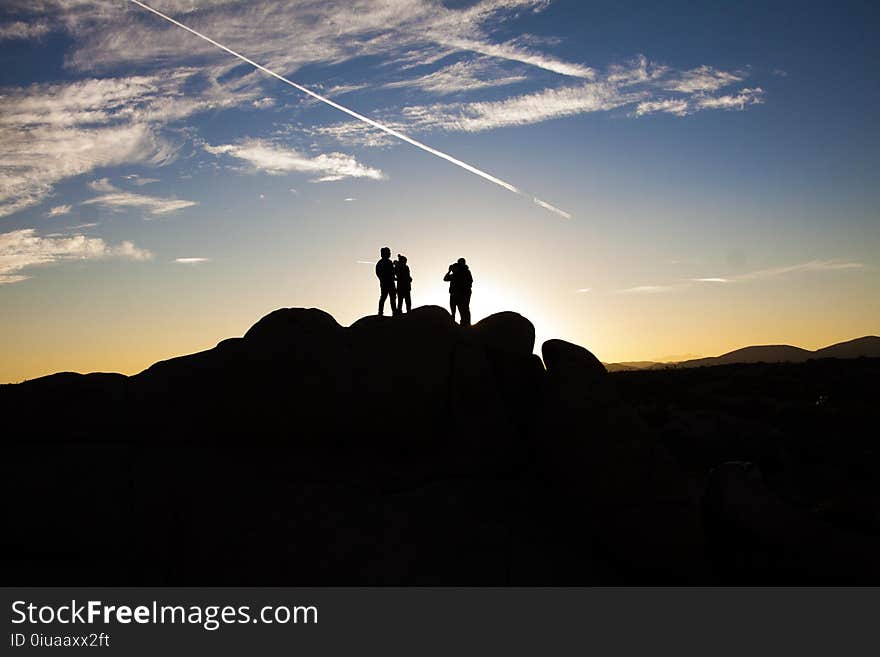 Silhouette Photo of People on Top of Rock Formation