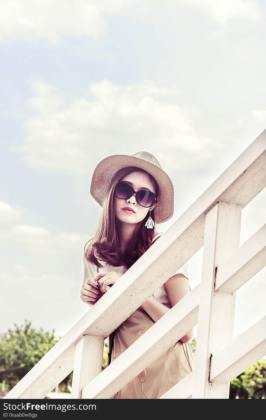 Woman Wearing Gray Sun Hat in Front of White Fence