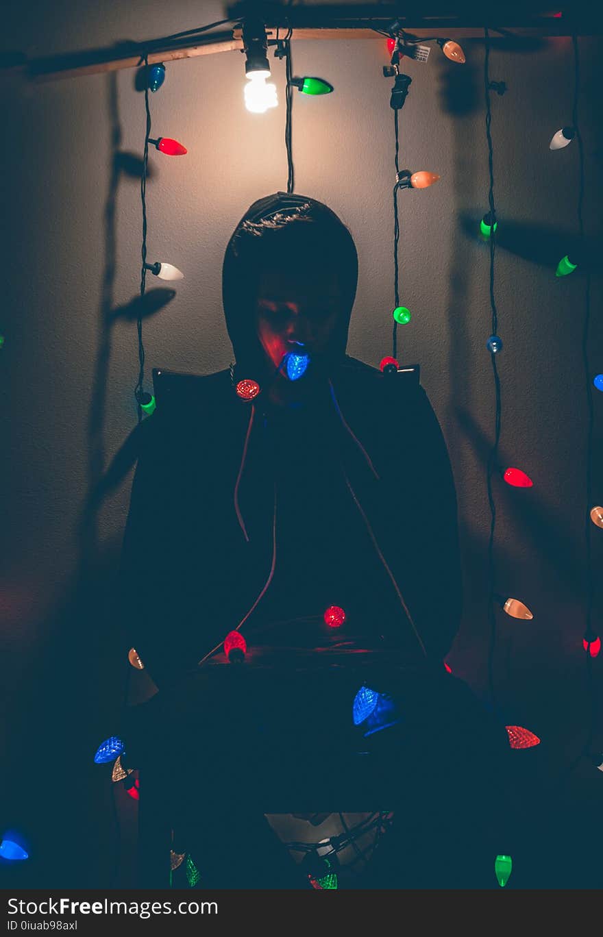 Man Sitting on Chair With Multi-colored String Lights