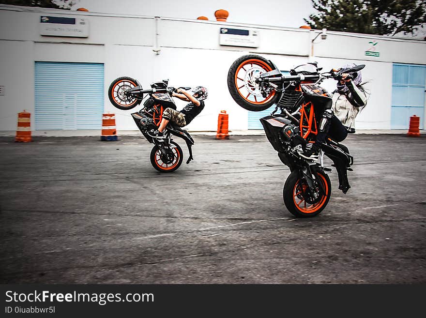 Two Men Riding Orange-and-black Sports Bikes While Doing Exhibition