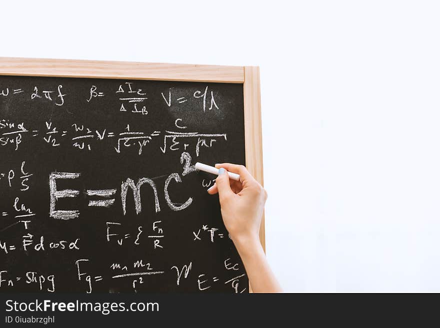 Person Holding a Chalk in Front of the Chalk Board