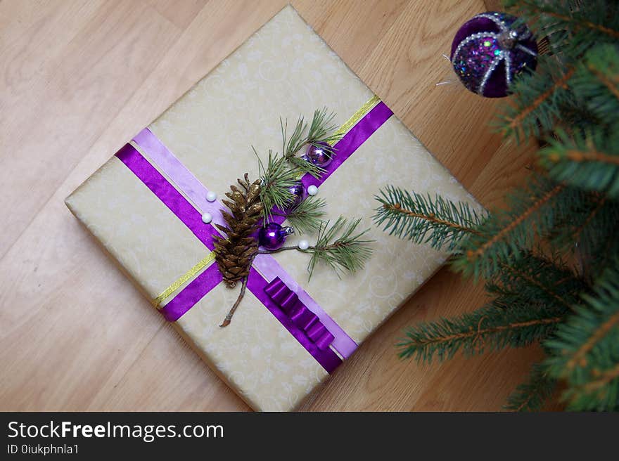 A beautifully packaged gift on the floor under the Christmas tree