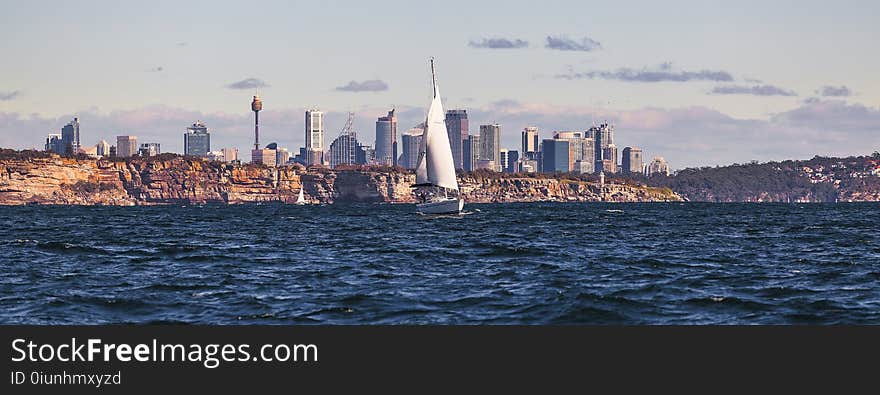 White Sailboat on Body of Water Near City