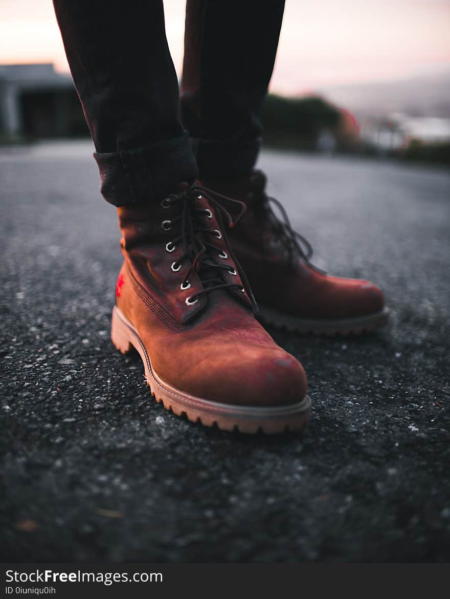 Person Wearing Pair of Brown Timberland Work Boots and Black Denim Skinny Jeans Standing on Asphalt Road