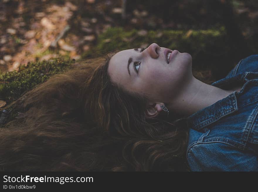 Photo of Woman Wearing Blue Denim Jacket Laying on Grass