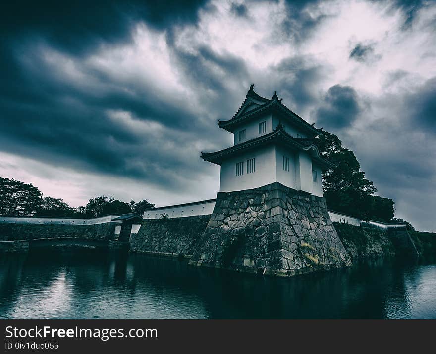 White and Black Concrete Building Near Body of Water Under Gray Cloudy Sky