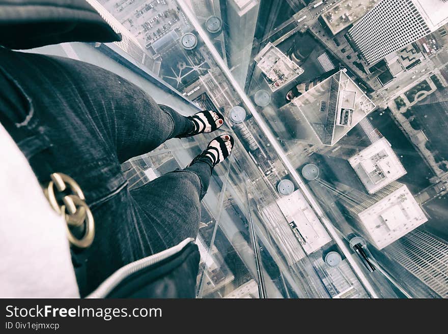 Woman in Blue Jeans Standing on Clear Glass