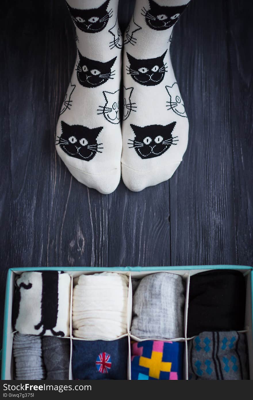 Feet selfie with black and white socks and a socks organizer on a dark wooden background. Top view